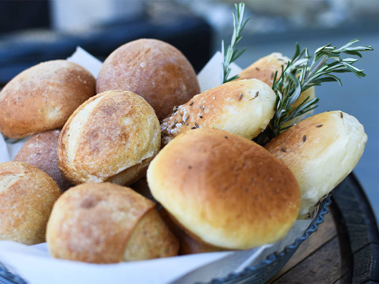 A basket overflows with rolls and herbs.