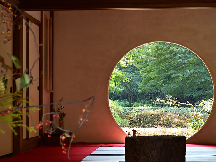 A photograph art piece of an empty room with a round open door open to a forest scene.