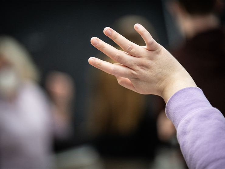 A hand is outstretched in a classroom.