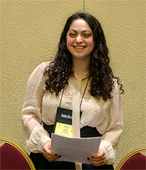 Student smiling holding packet of papers.