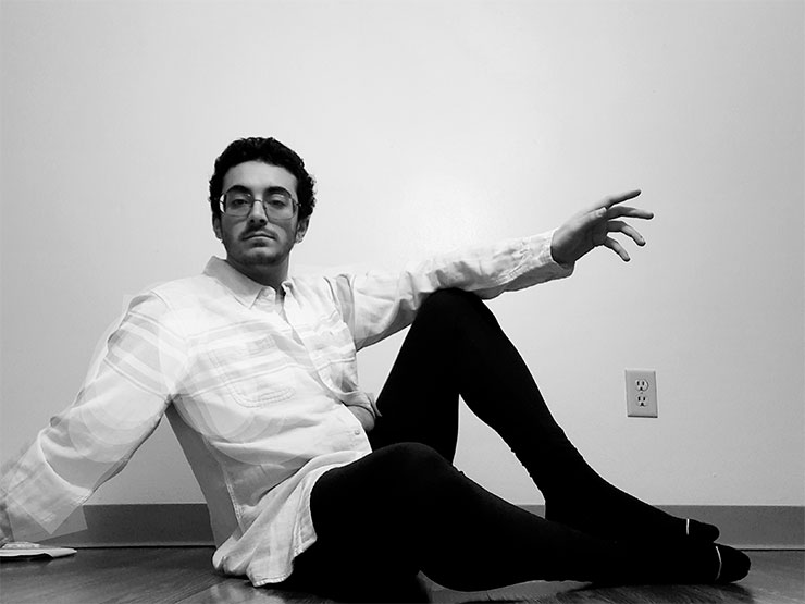 A college student poses on the ground in a black and white image.