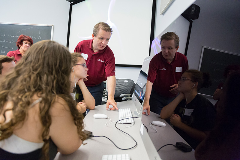 Professor and students seated around computer work station.