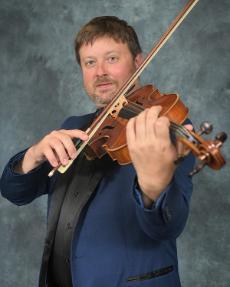 Adjunct faculty member, J.J. Johnson, posing with string instrument.