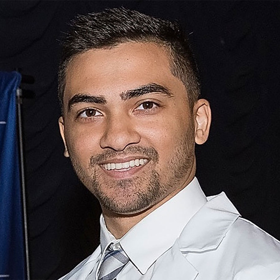 A smiling man in white collared shirt with a tie smiles at the camera.