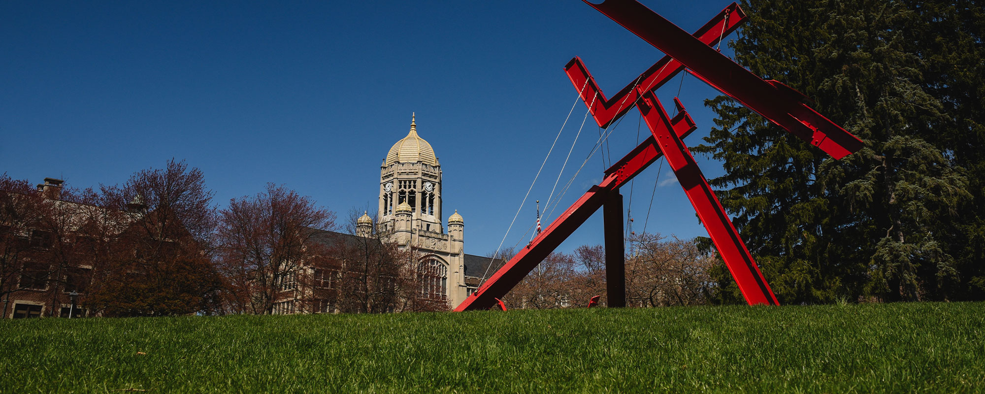 Haas College Center and the red modern sculpture Victors Lament stand against a dark blue sky on the campus of Muhlenberg College.