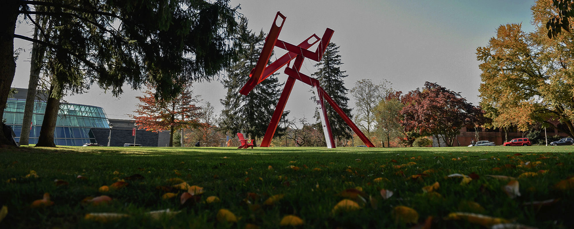 A red Adirondack chair sits beneath the red modern sculpture Victors Lament at Muhlenberg College.