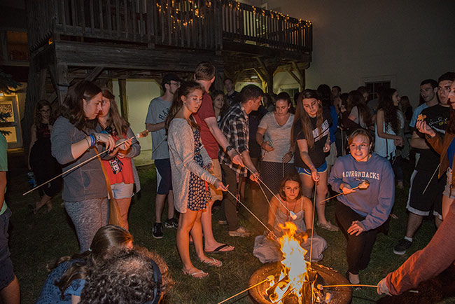 Student roasting marshmallows over an open fire.