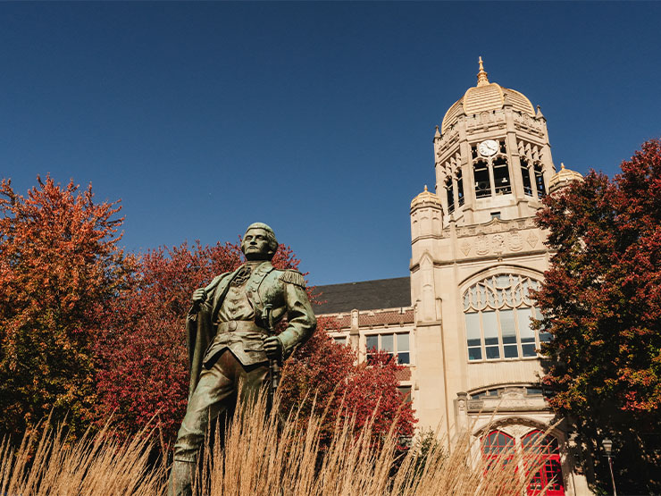 A statue of General Muhlenberg stands in front of Haas College Centre among fall foliage.