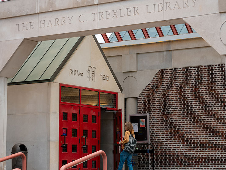 A college student opens red doors to Trexler Library.