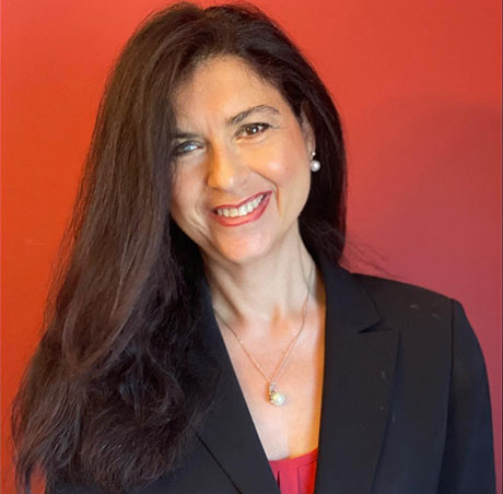 Office of Multicultural Life staff member Tina Guida standing in front of red backdrop.