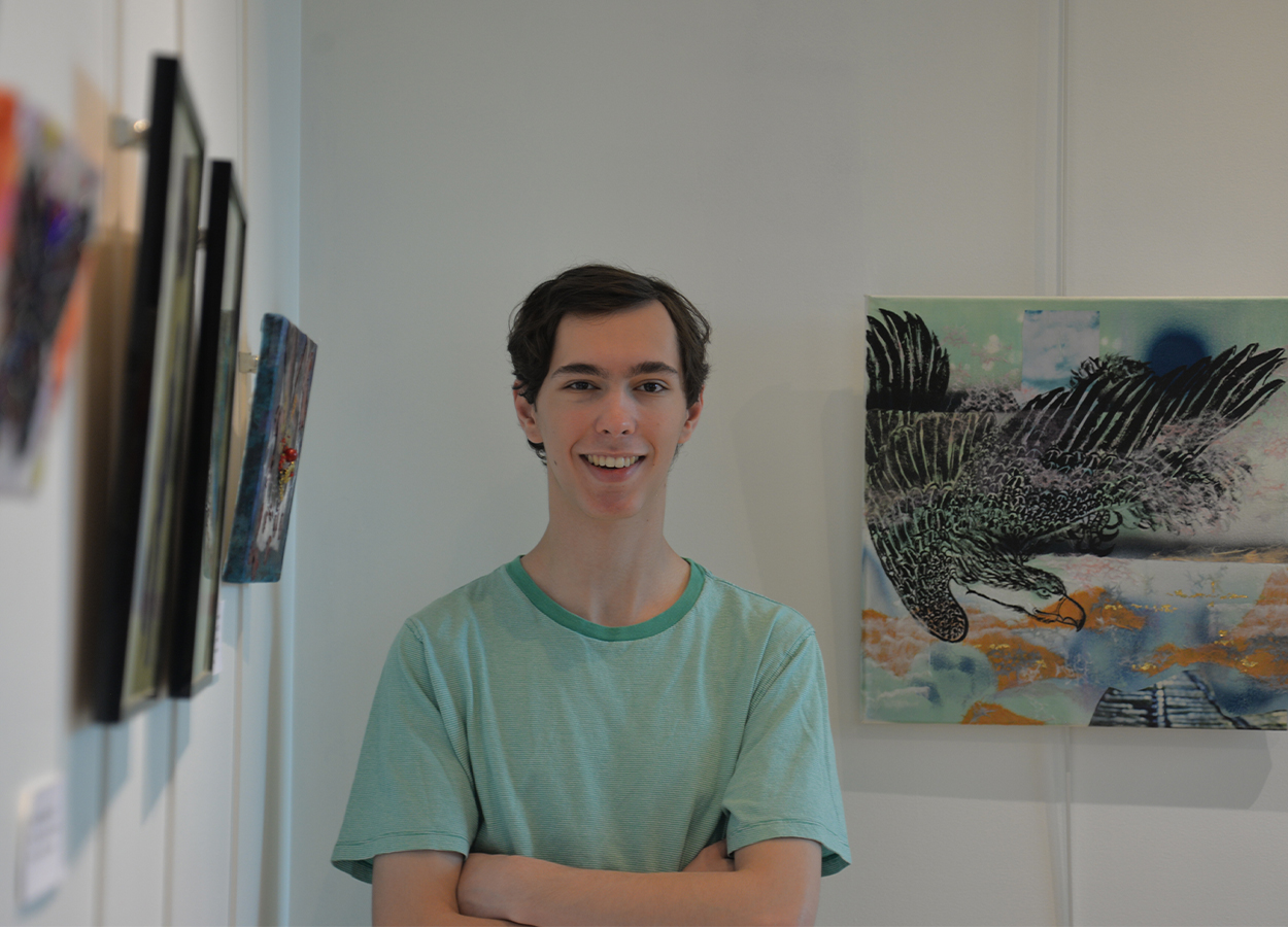 A student stands, arms crossed, in an art gallery.