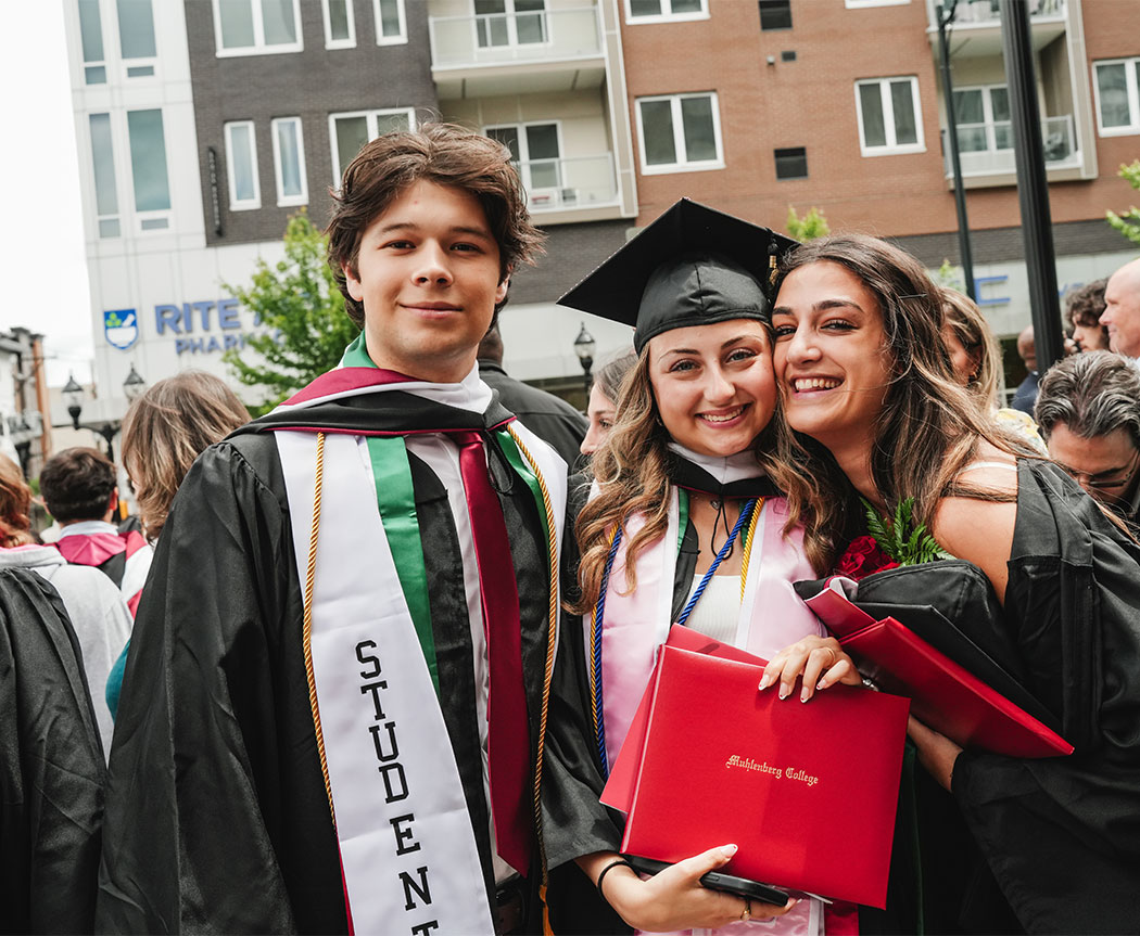 A trio of recent graduates pose together and smile outside of the PPL Center in downtown Allentown.