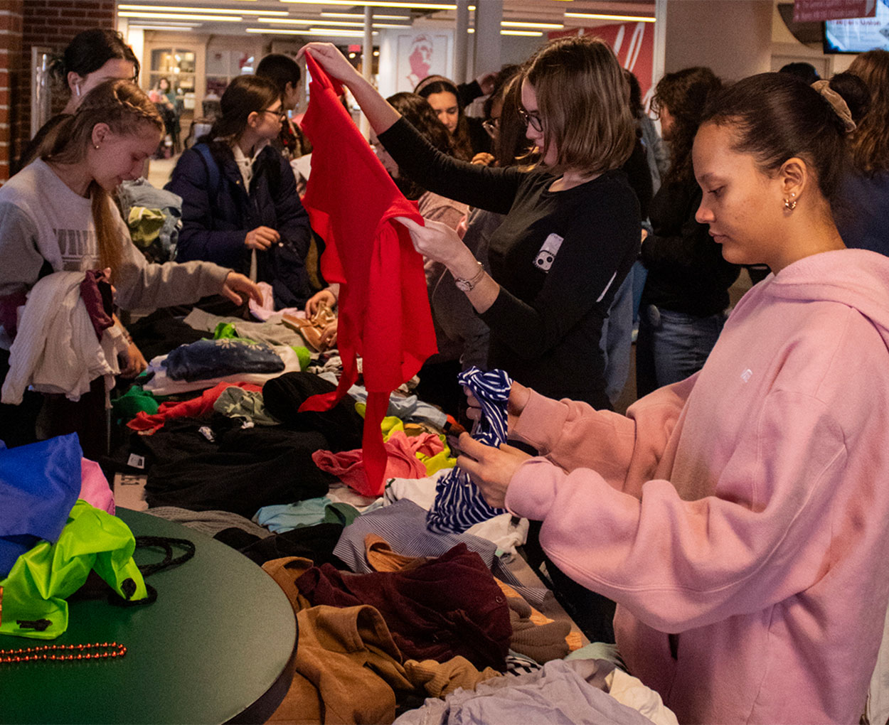 Students gather around and sift through tables piled with clothing.