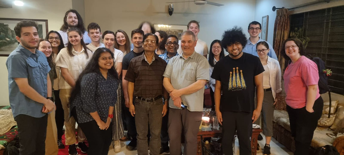 A large group of college students, faculty, and other adults visit inside a home