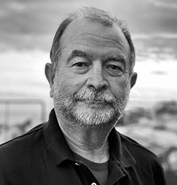 A black and white headshot of Tom Graves, who is wearing a dark shirt