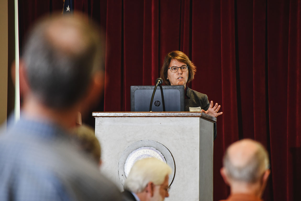 A college professor speaks at a podium in front of an audience