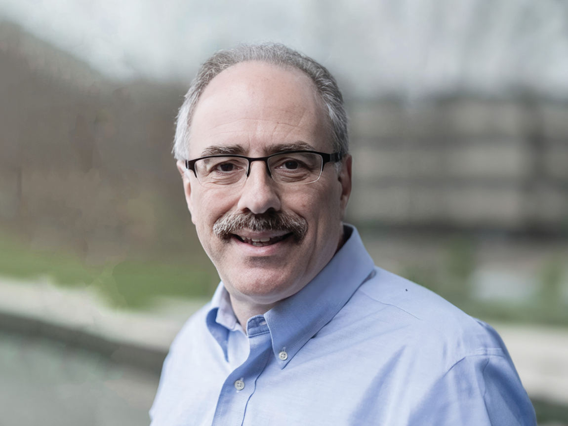 A headshot of Dr. Leonard Zon, who has glasses and a mustache and a blue shirt on